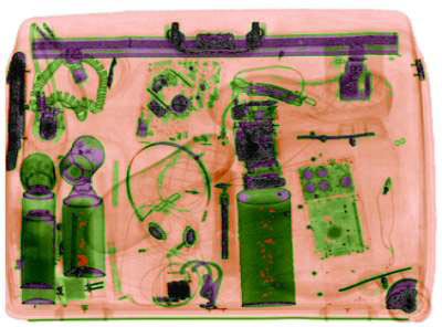 
							
								X ray image of a bag. Shaded in green, a pair of headphones, a cord, a razor, and other objects are discernible. Several objects have orange areas shaded. 
							
							